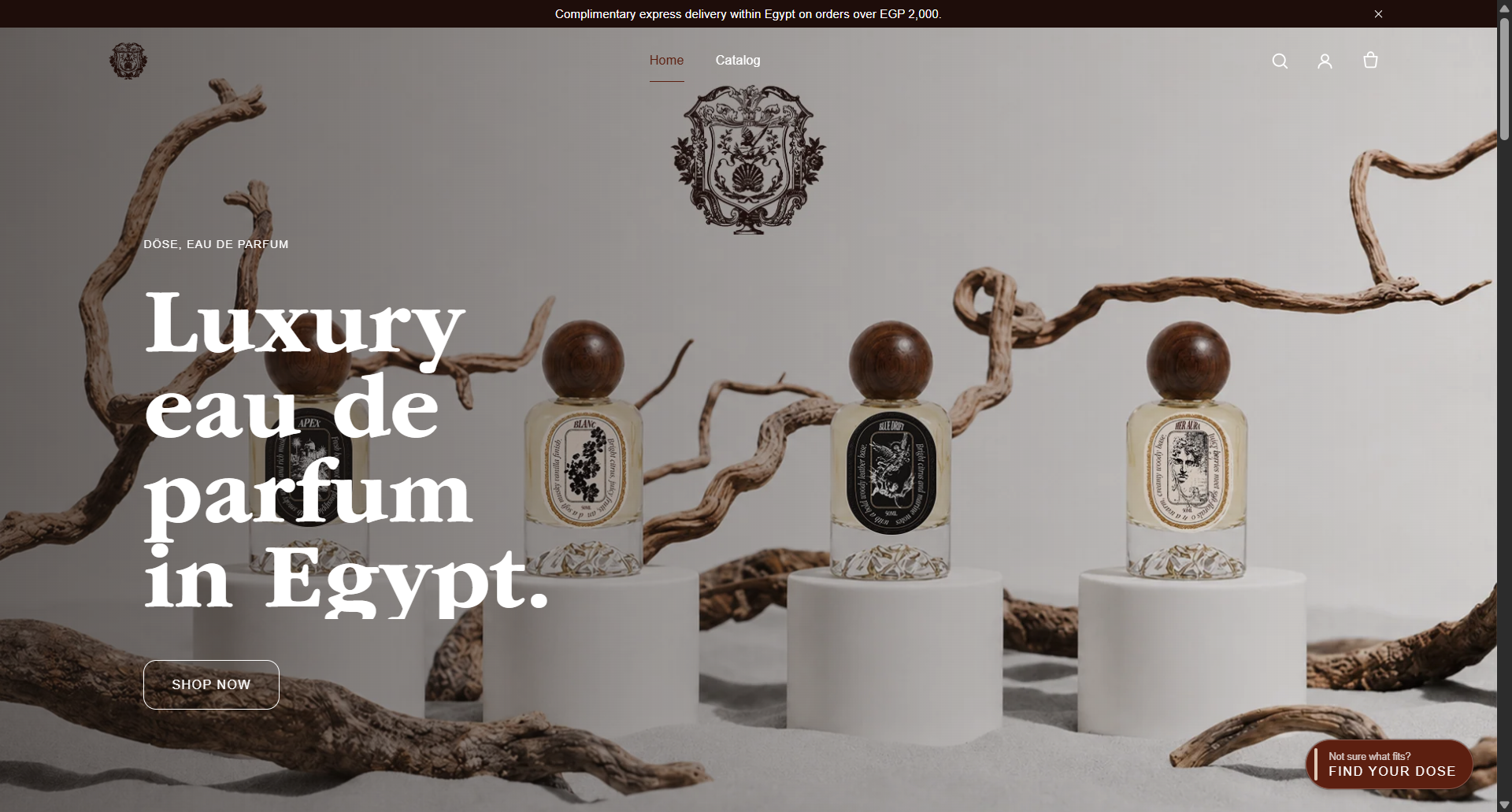 DÖSE homepage hero: luxury eau de parfum bottles staged as still life on sand with driftwood